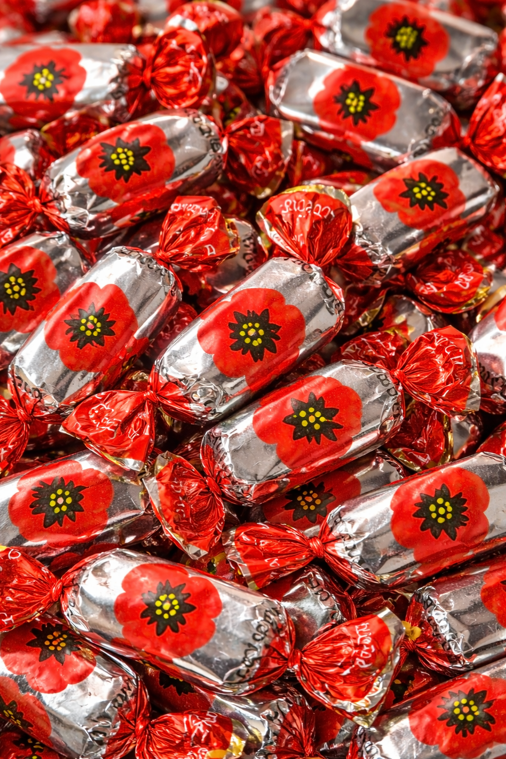 Close up of Pergalė Raudonoji Aguona chocolate candies with red poppy design wrapper, chocolate coated sweets with poppy seed filling, Lithuanian confectionery detail